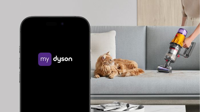 Vlevo telefon s aplikací MyDyson, vpravo vysávání pohovky, na které leží kočka