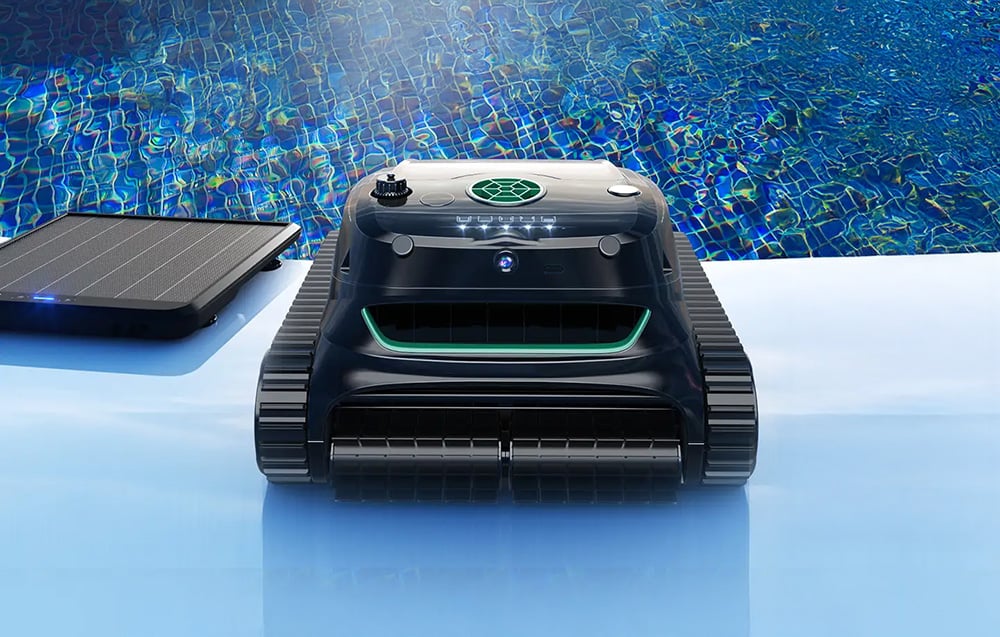 Bazénový robot Wybot na okraji bazénu vedle solárního panelu.