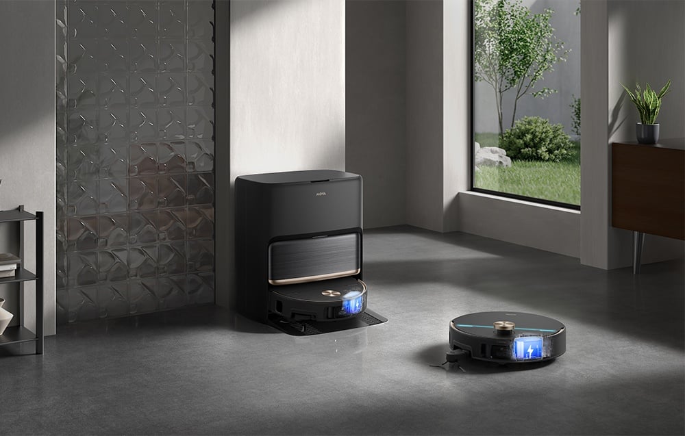 Černý robotický vysavač se nabíjí v dokovací stanici umístěné v moderním obývacím pokoji.